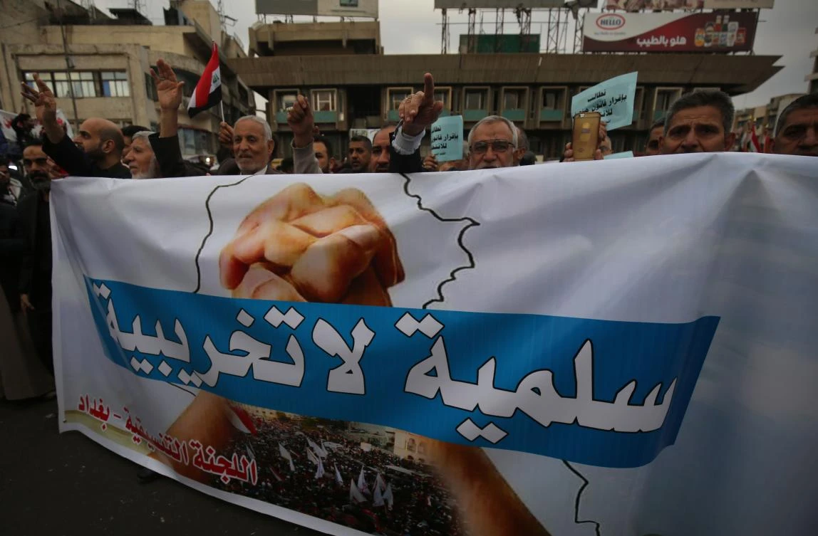Demonstrators carry a large banner that says in Arabic ‘peaceful, not destructive’ as they take part in an anti-government demonstration in Baghdad’s Tahrir Square on December 6, 2019. (AFP)
