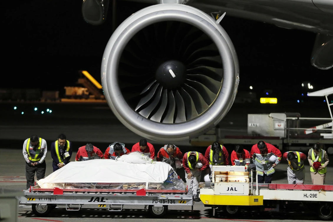 Airport workers bow to pay respect to the coffin of late Japanese doctor Tetsu Nakamura at Narita International Airport in Chiba, Japan on Sunday December 8, 2019. (Kyodo via Reuters)
