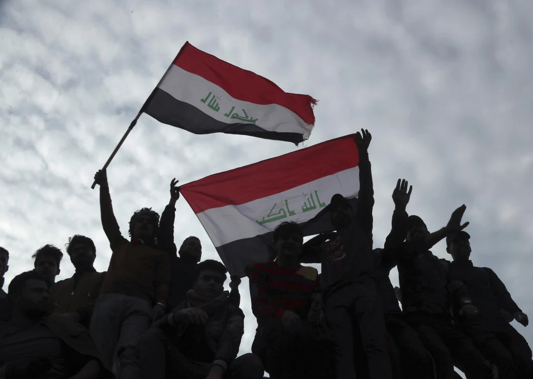 Protesters chant anti government slogans and fly Iraqi flags during minor clashes with Iraqi riot police, at a bridge in Baghdad, Iraq, Tuesday, Dec. 10, 2019. (AP)