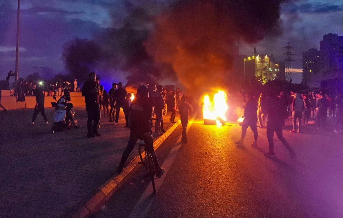 Lebanese anti-government protesters burn tyres to block a road in al-Mina town in the northern port city of Tripoli on December 10, 2019 following the collapse of a house overnight in the area that killed two siblings. (AFP)