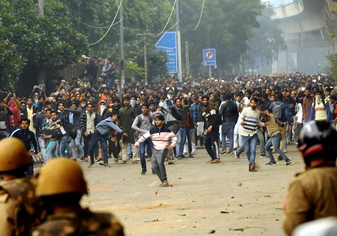 Students pelt stones outside the Jamia Millia Islamia University in New Delhi, India, during a protest against the Citizenship Amendment Bill on Friday. (AP Photo)