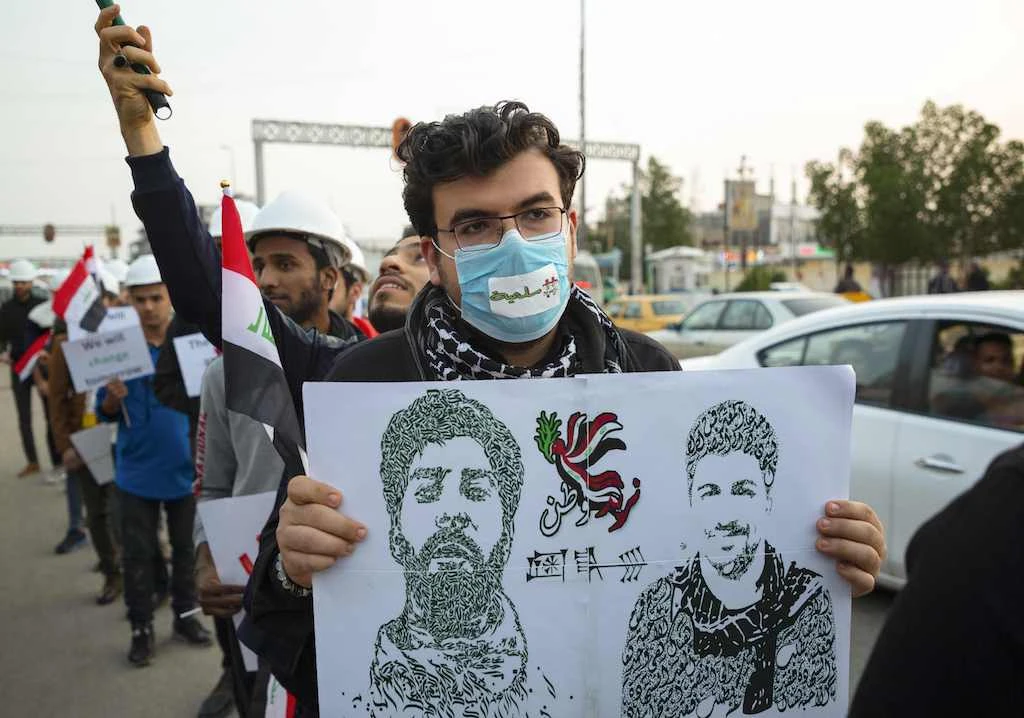 An Iraqi man carries a placard depicting protesters who died during ongoing anti-government demonstrations, at a rally near the local government headquarters in the southern city of Basra, on December 13, 2019. (AFP)