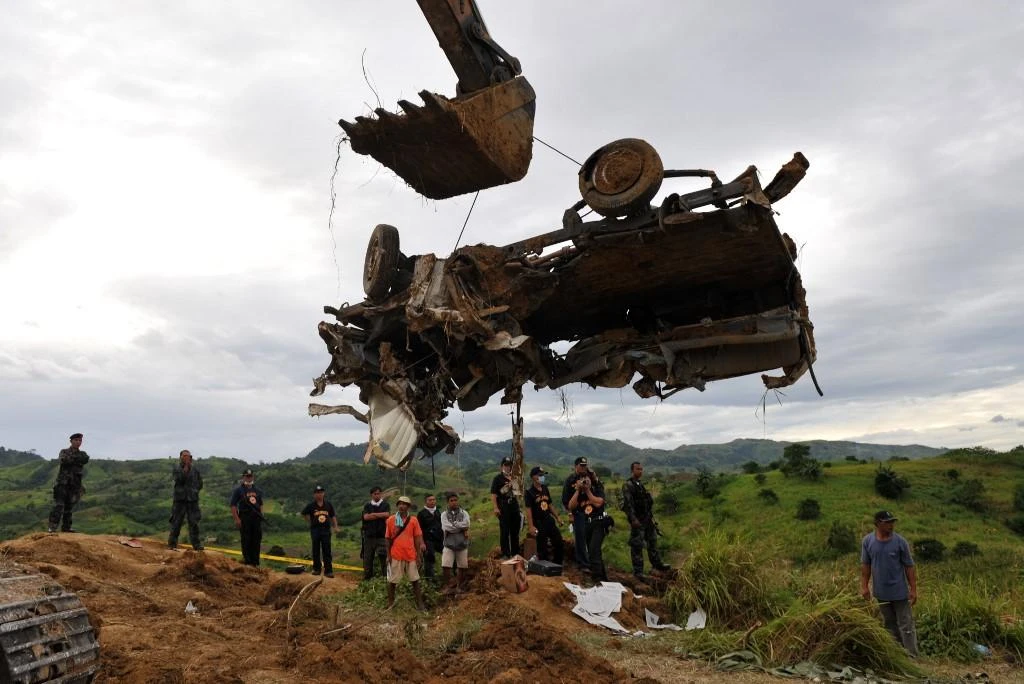 A backhoe lifts a mangled vehicle unearthed from a shallow grave on November 25, 2009 in the Philippines’ worst political killing wherein 58 people, including 32 media workers, were massacred. (AFP file photo)