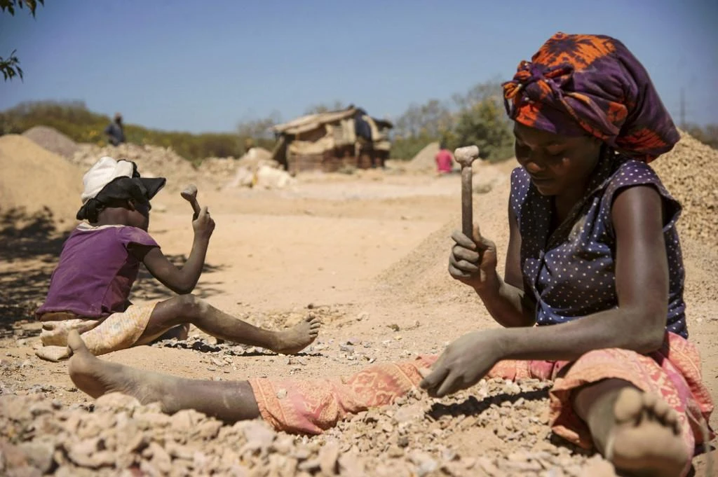 A child and a woman break rocks extracted from a cobalt mine at a copper quarry and cobalt pit in Lubumbashi, Democratic Republic of the Congo on May 23, 2016. (AFP)