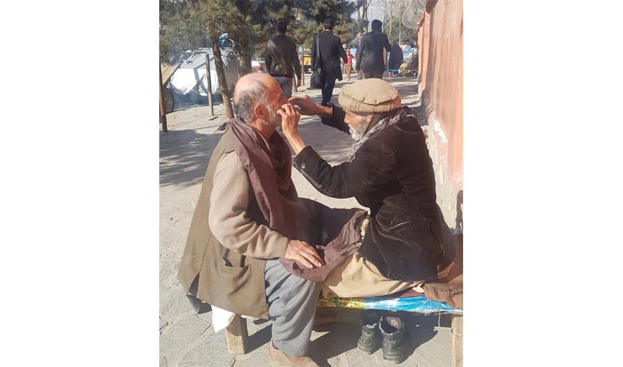 A roadside barber trims a customer’s hair in Kabul. (AN photo)