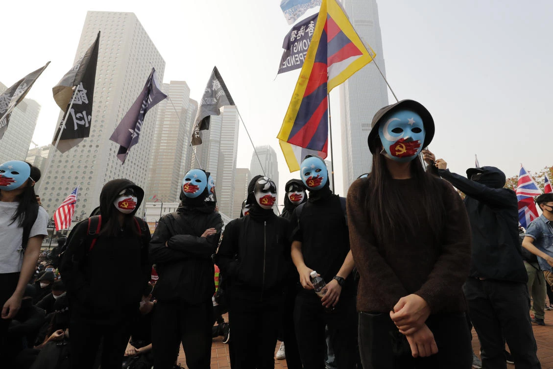 More than 1,000 people rallied early Sunday, dressed in black and wearing masks to shield their identities and waving Uighur flags and posters. (AP)