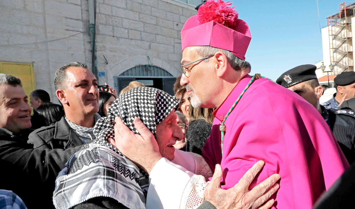 Pierbattista Pizzaballa, apostolic administrator of the Latin Patriarchate of Jerusalem, kisses the head of an elderly Palestinian man in Bethlehem. (AFP)