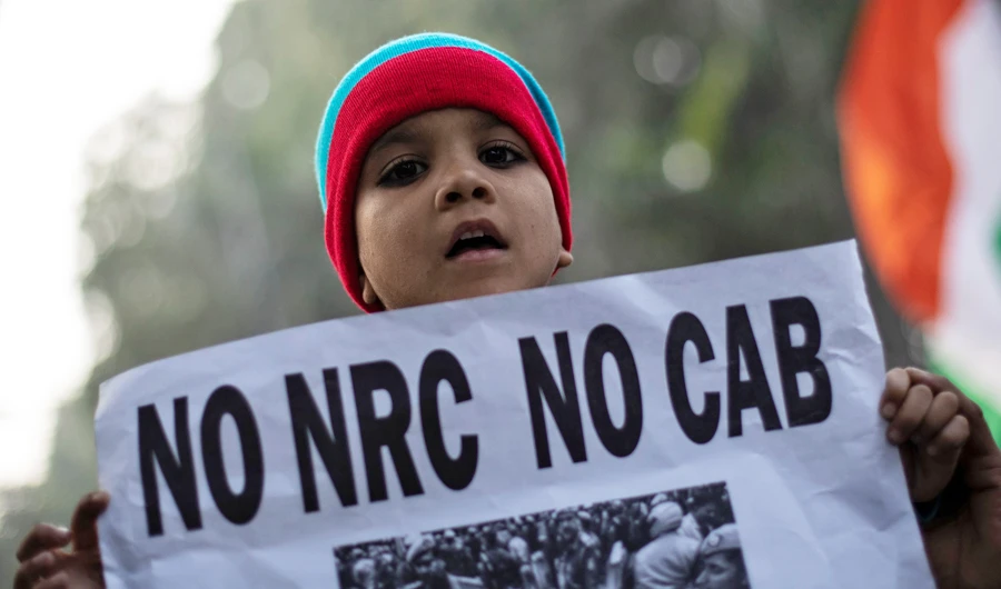 A boy holds a placard during a protest against a new citizenship law, outside the Jamia Millia Islamia university in New Delhi, India, December 22, 2019. (REUTERS)