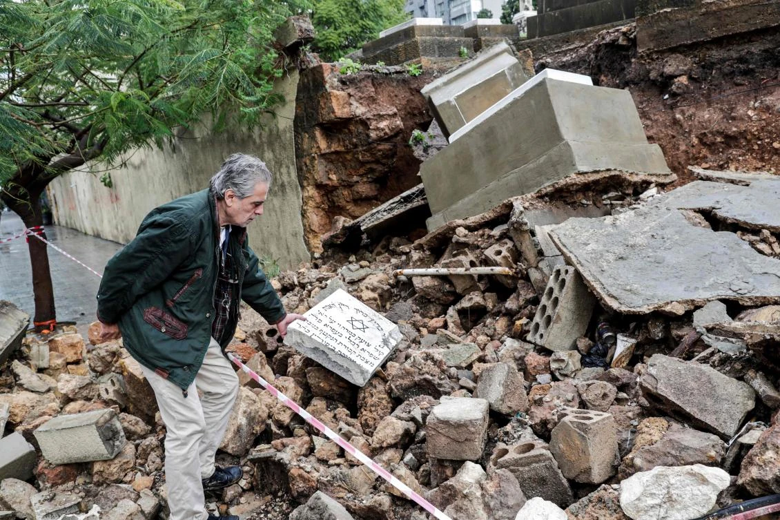 Nagi Georges Zeidan, an expert on the Jewish community in Lebanon and a volunteer at Jewish cemetery in the capital Beirut, inspects a broken tombstone at the site after several graves were damaged during bad weather in a winter storm on December 26, 2019. (File/AFP)