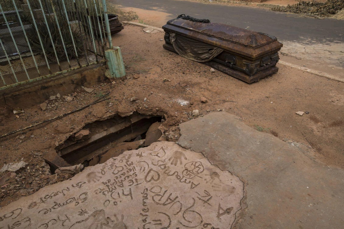 An oxidized coffin lies next to a grave that was dug up by thieves at “Corazon de Jesus” cemetery, or Heart of Jesus cemetery, in Maracaibo, Venezuela, Nov. 21, 2019. Thieves often raid graves for valuables, while public cemeteries often go abandoned, overgrown with weeds. (AP/Rodrigo Abd)