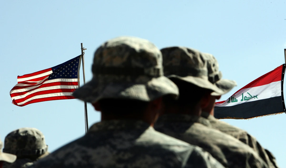 US troops stand to attention in front of American and Iraqi (R) flags during a handover ceremony in Kirkuk province. (File/AFP)