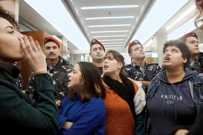 Policemen stand guard as anti-government protesters shout slogans inside a branch of Bank Audi on Monday. (AP)