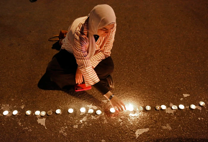 An anti-government protester lights candles in the middle of a blocked road in Beirut during ongoing protests against the Lebanese political class and the financial crisis on Dec. 4, 2019. (AP Photo/Hussein Malla)