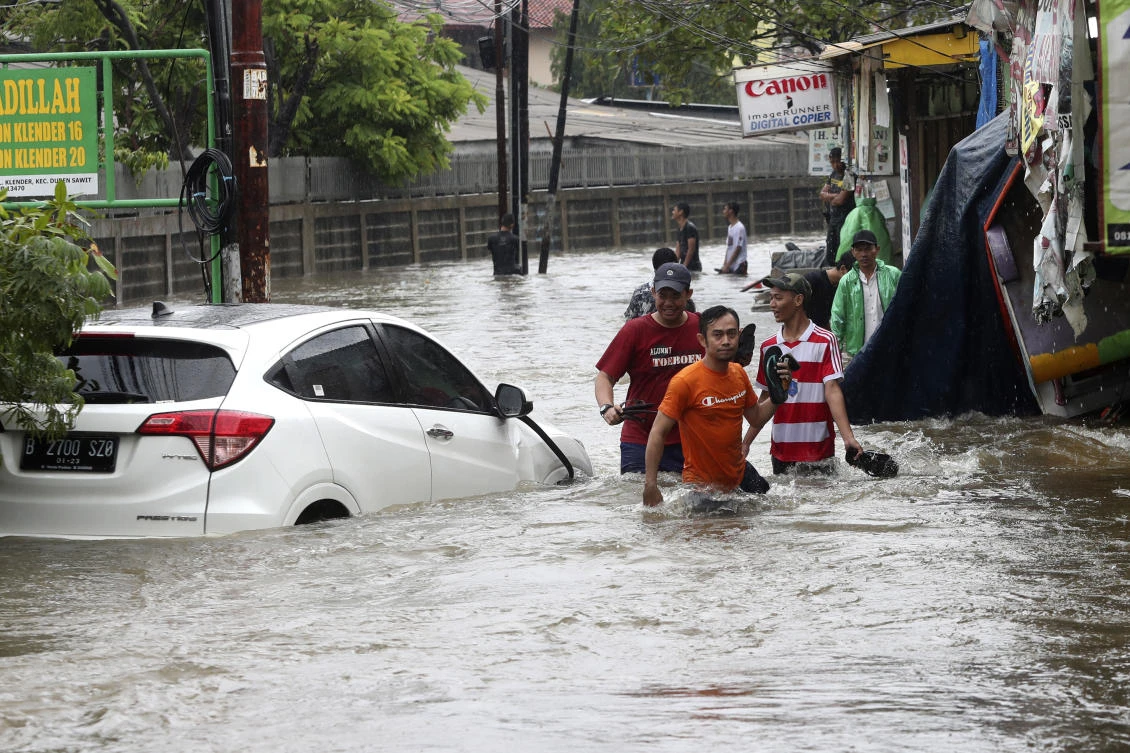 Indonesian people wade through floodwaters in Jakarta, Indonesia, Wednesday, Jan. 1, 2020. (AP)