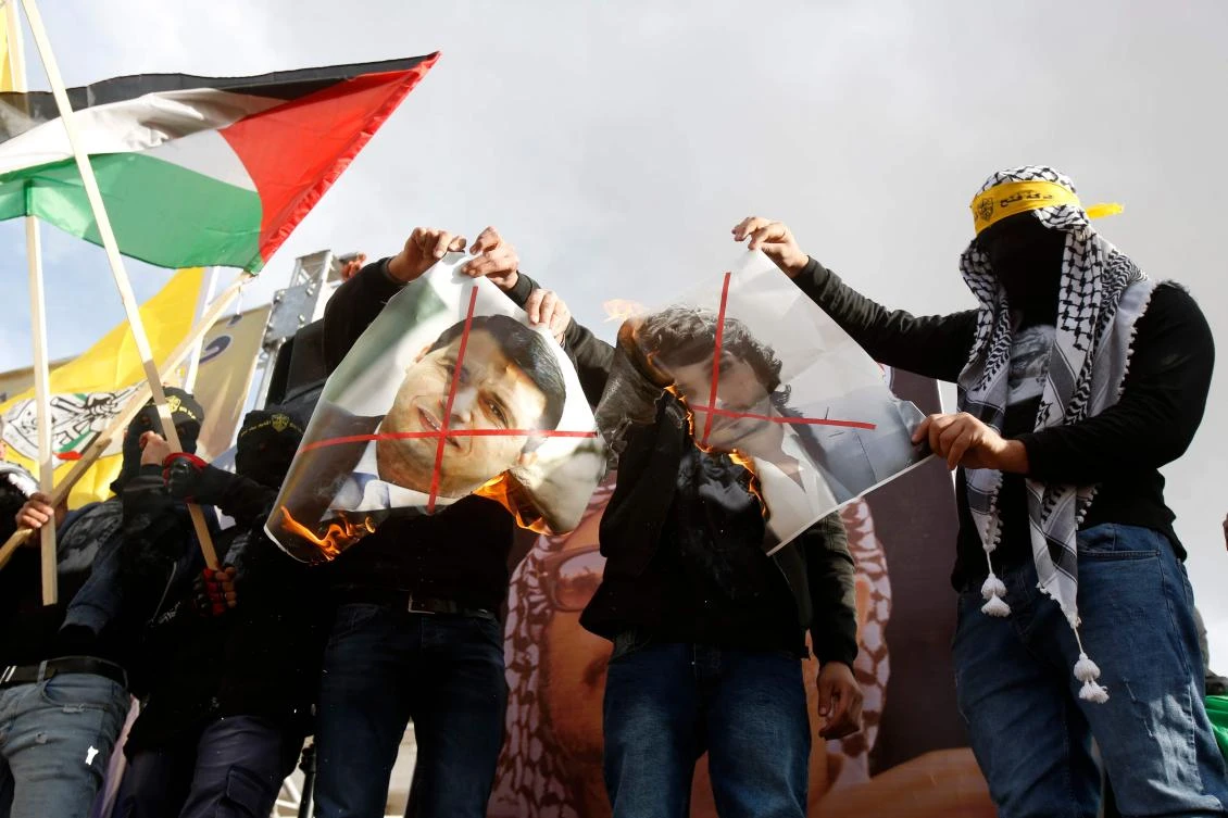 Supporters of the Palestinian Fatah movement burn a picture of exiled Palestinian politician Mohammed Dahlan during a rally marking the 55th foundation anniversary of the political party in the West Bank town of Bethlehem on January 1, 2020. (AFP)