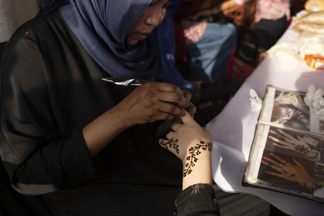 In this June 20, 2019 photo, a Sudanese woman applies henna to a Yemeni girl's hand during an event marking the U.N.'s International Refugee Day, in Cairo, Egypt. (AP)