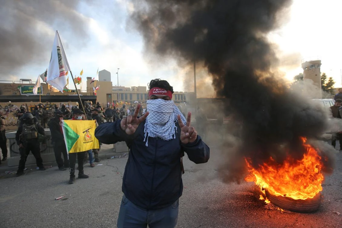 A supporter of Iraq's Hashed al-Shaabi paramilitary force flashes victory signs during a protest outside the US embassy in the Iraqi capital Baghdad on January 1, 2020 to condemn the US air strikes that killed 25 Hashed fighters over the weekend. (AFP)