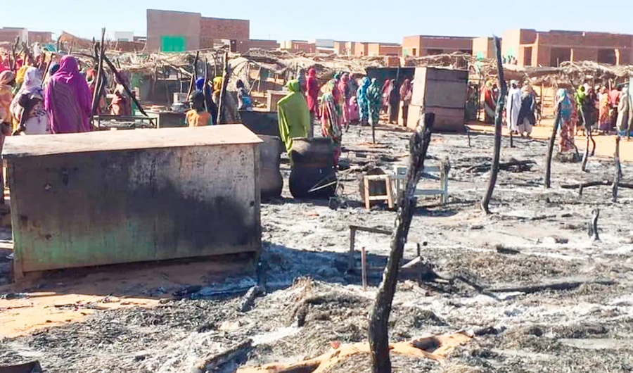 In this Sunday, Dec. 29, 2019 photo, residents of a refugee camp gather around the burned remains of makeshift structures, in Genena, Sudan. (AP)