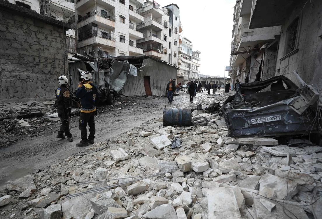 Syrian rescuers known as the White Helmets walk amidst the rubble scattered across a street following a reported regime air strike in the town of Ariha in the Idlib province on January 5, 2020, killing at least 9 civilians. (AFP)