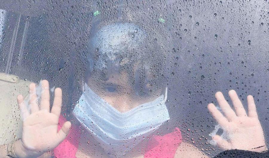 A girl wearing a mask looks out a car window as rain drops are seen in Taif June 7, 2014. (REUTERS)