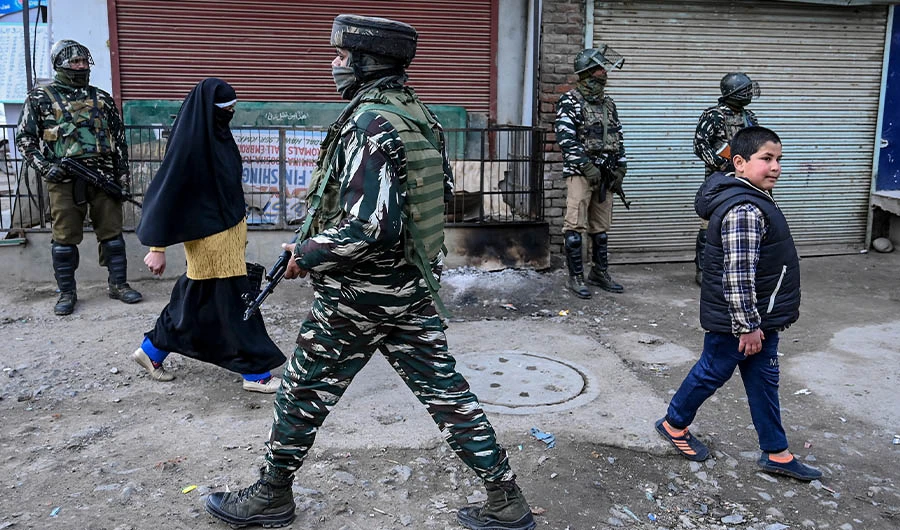 Security personnel stand guard on a street as residents walk by, after a grenade blast in Srinagar on January 4, 2020. (AFP)
