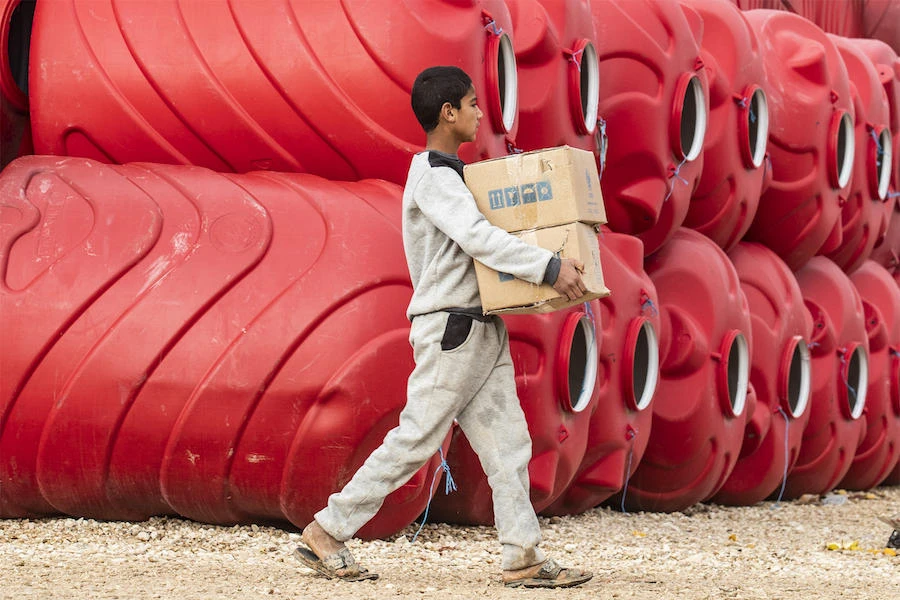 A boy carries humanitarian aid packages in the al-Hasakeh governorate in northeastern Syria. (File/AFP)