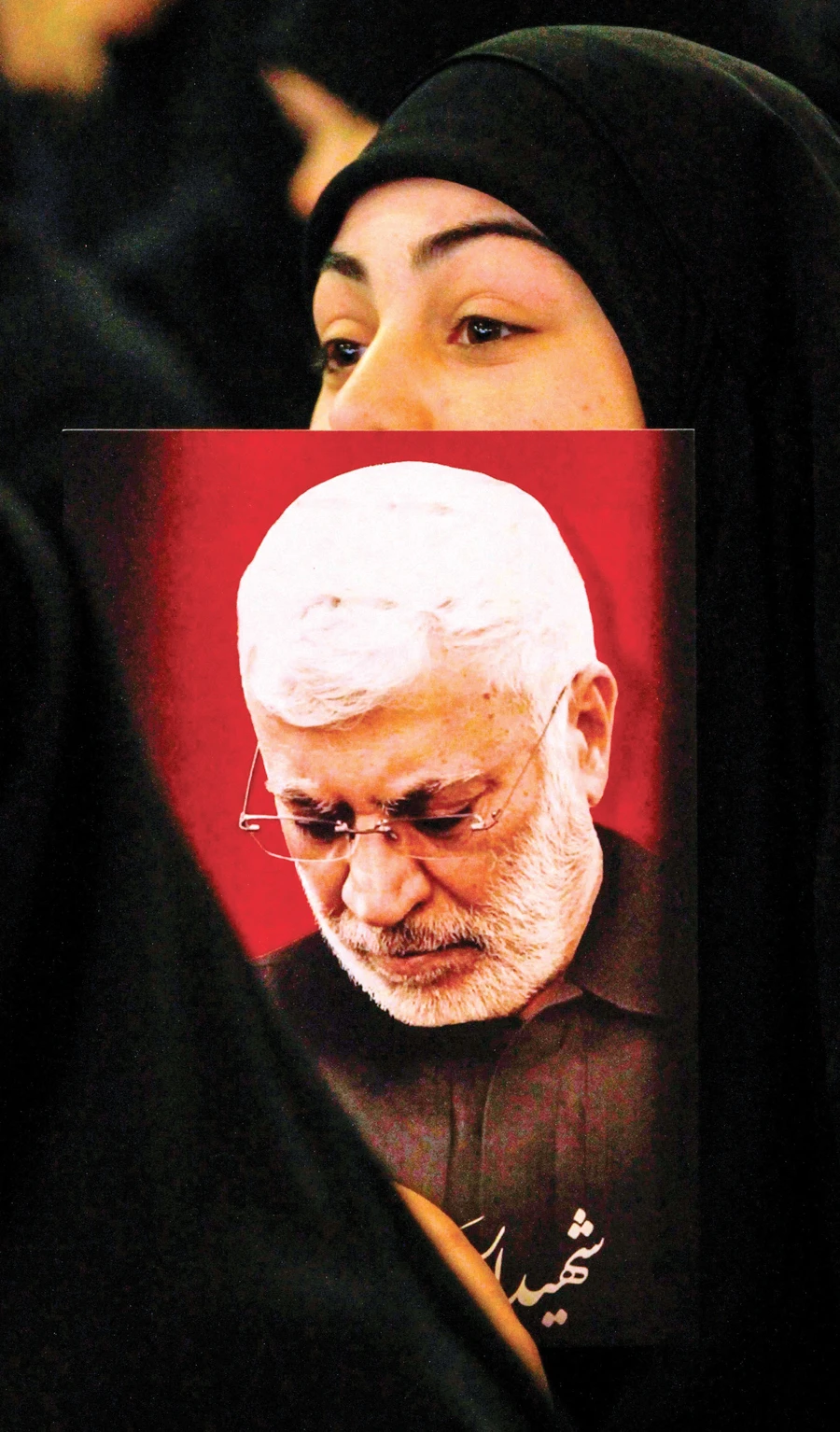A Hezbollah supporter, carrying a portrait of Abu Mahdi Al-Muhandis, slain chief of the Hashd Al-Shaabi militia, watches as Hezbollah leader Hassan Nasrallah delivers a speech on a screen in Nabatieh, Lebanon on Sunday. (AFP)