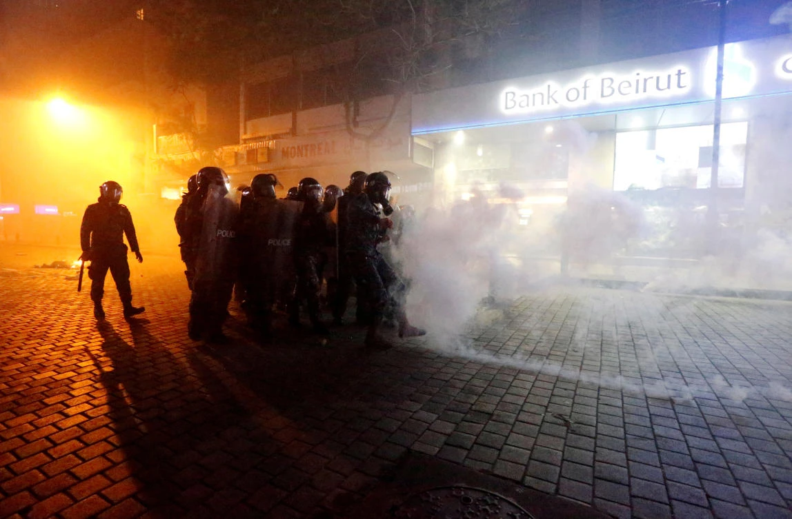 Riot police officers stand behind riot shields amid a cloud of tear gas during protests against the economic crisis outside a Bank of Beirut office in Beirut, Lebanon January 14, 2020. (Reuters)