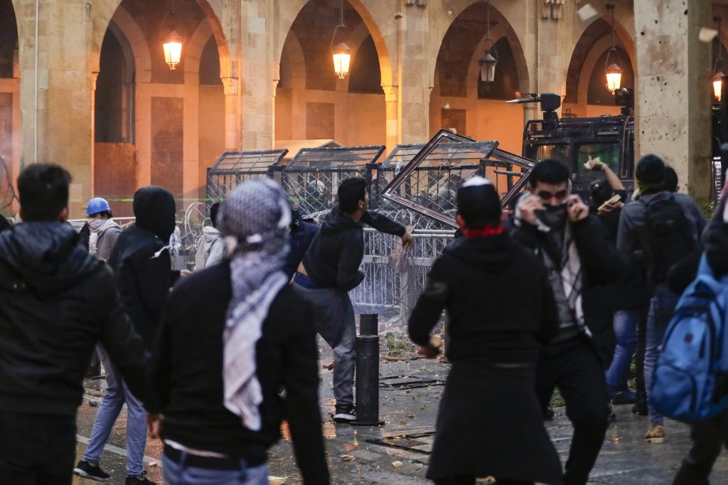 Anti-government protesters attempt to break through the security barrier in the central downtown district of Beirut near the parliament headquarters during clashes with security forces on January 18, 2020. (AFP)
