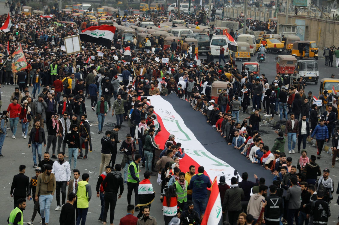 University students hold a huge Iraqi flag during ongoing anti-government protests in Baghdad on Sunday, January 19, 2020. (Reuters)