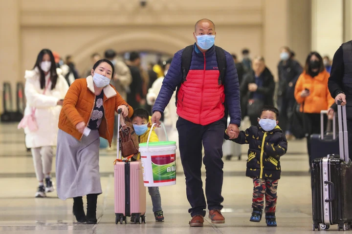 Travelers wearing face masks walk with their luggage at Hankou Railway Station in Wuhan in southern China's Hubei province. (AP)