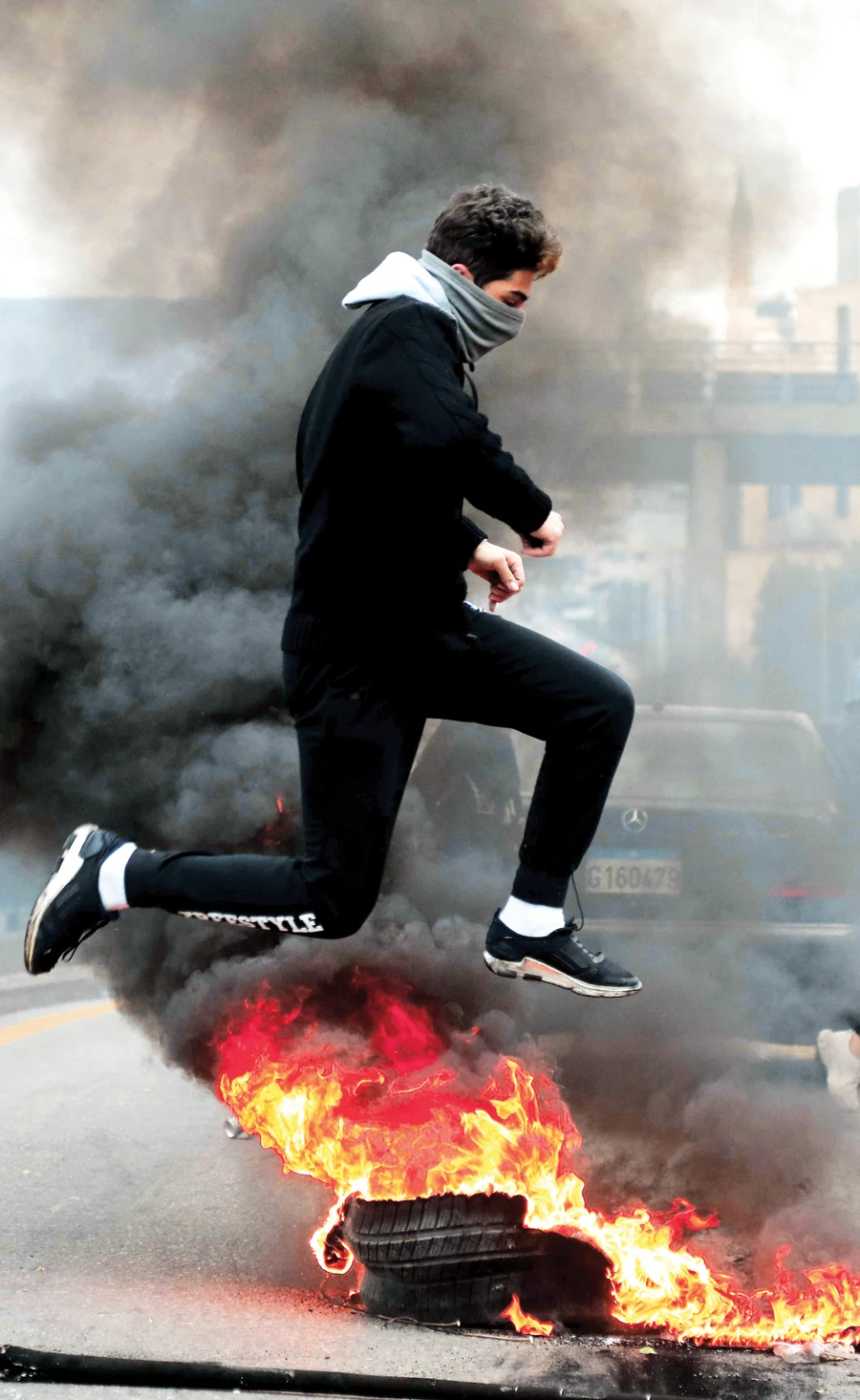 A Lebanese protester jumps over a roadblock near the Camille Chamoun Sports City Stadium in Beirut on Thursday. (AFP)