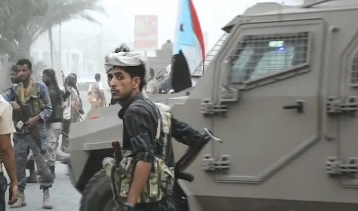 A fighter stands in front of an armored vehicle in the center of Aden . (AP)