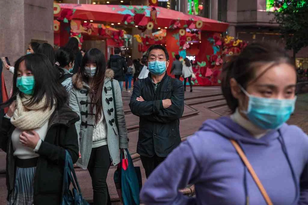 People wearing masks stand on a street in a shopping district in Hong Kong on January 26, 2020, as a preventative measure following a coronavirus outbreak which began in the Chinese city of Wuhan. (AFP)