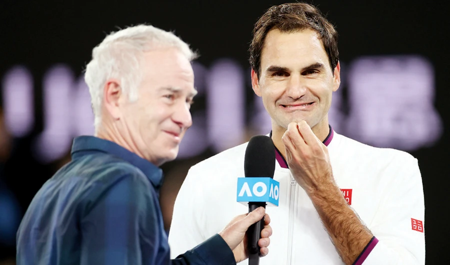 Roger Federer talks with former tennis player John McEnroe after his match against Marton Fucsovics. (Reuters)