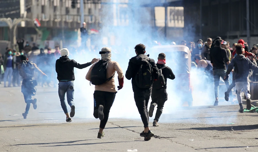 Iraqi protesters rush to catch a tear gas canisters fired by security forces during clashes following an anti-government demonstration in Al-Khilani square in the capital Baghdad, on January 26, 2020. (AFP)