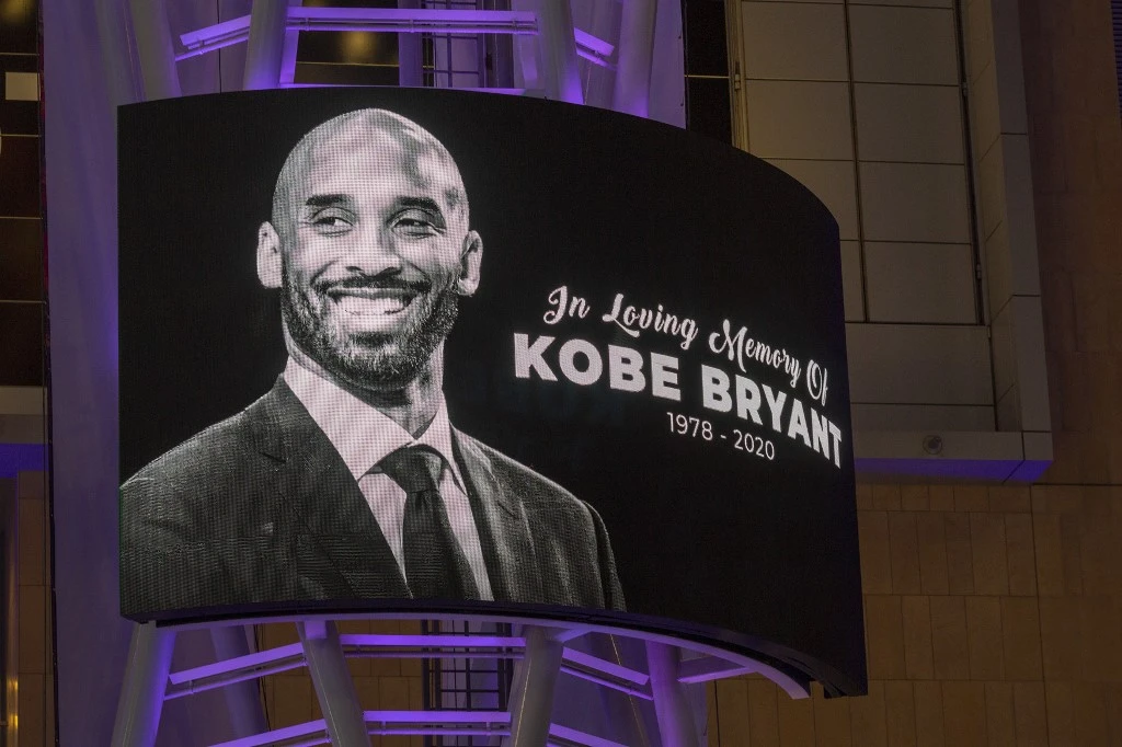 Memorial signage hangs near people mourning for former NBA star Kobe Bryant, who was killed in a helicopter crash in Calabasas, California. (AFP)