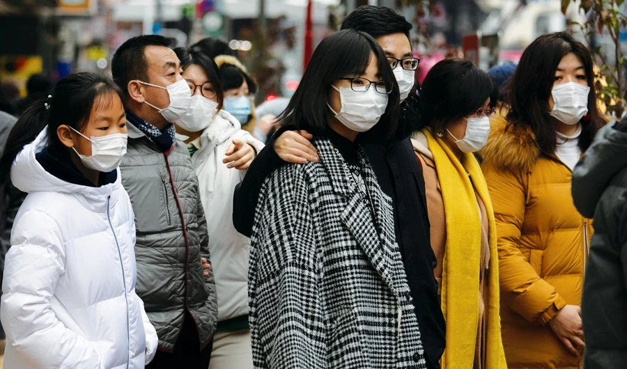 Chinese tourists wearing protective face masks wait to board a Tokyo train. Japanese exporters are worried the virus outbreak will hit earnings. (AP)