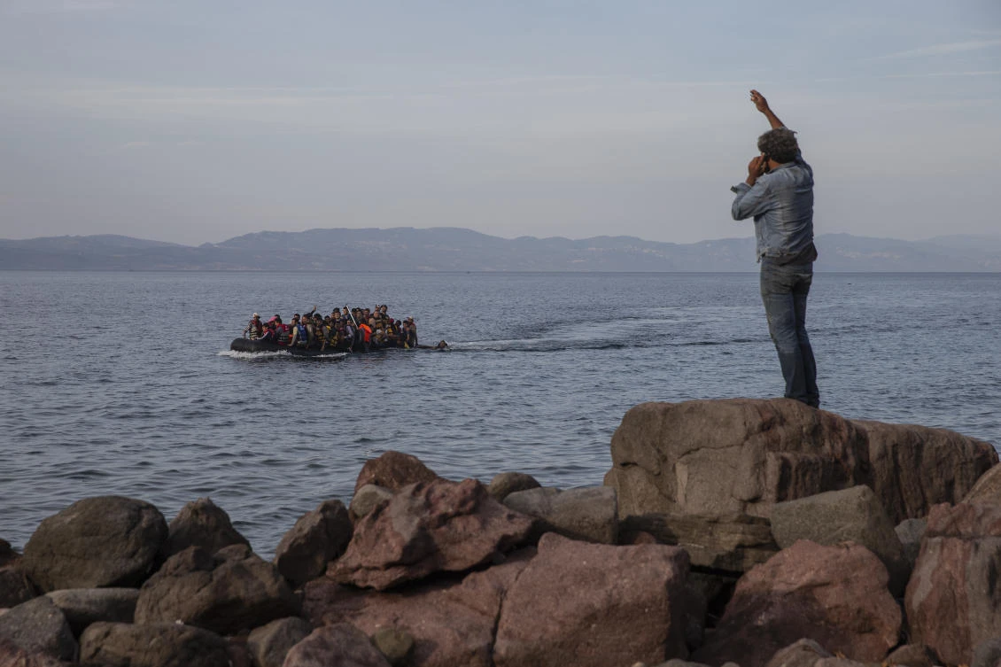 Refugees and migrants aboard an overcrowded dinghy as they cross the Aegean Sea, from Turkey, seen in the background, to the coast of Lesbos island, Greece. (AP Photo)