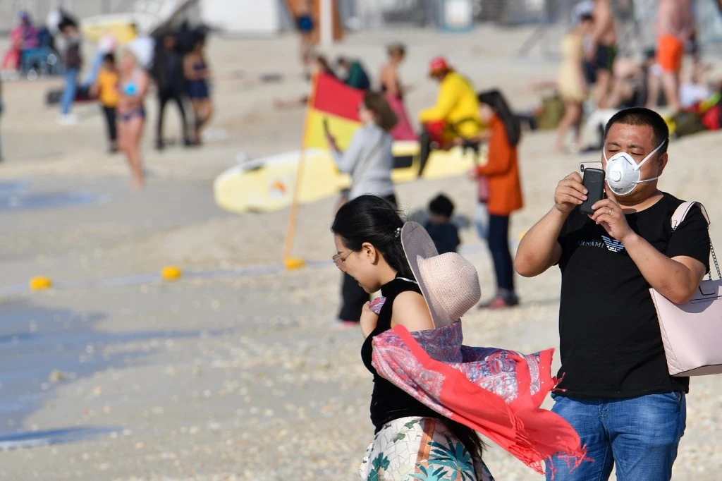 The recent coronavirus outbreak has led to a surge of people wearing face masks - as seen here being worn by Chinese tourists on a beach near Dubai's Burj Al-Arab - but experts have warned the masks would not be sufficient to prevent infection. (AFP)