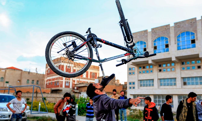 Yemeni street artist Salim el-Maghrabi balances a bicycle on his chin while performing in public in the Sanaa, where an Internet outage has crippled a lot of businesses in the past three weeks. (/ AFP / MOHAMMED HUWAIS)