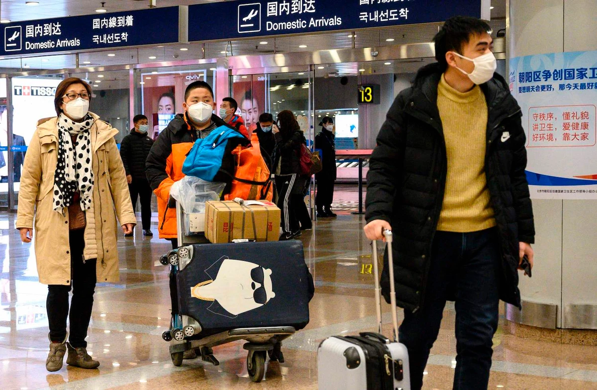 Passengers, wearing protective facemasks, walk at the arrival area of the Beijing Capital International airport on January 31, 2020. (AFP)