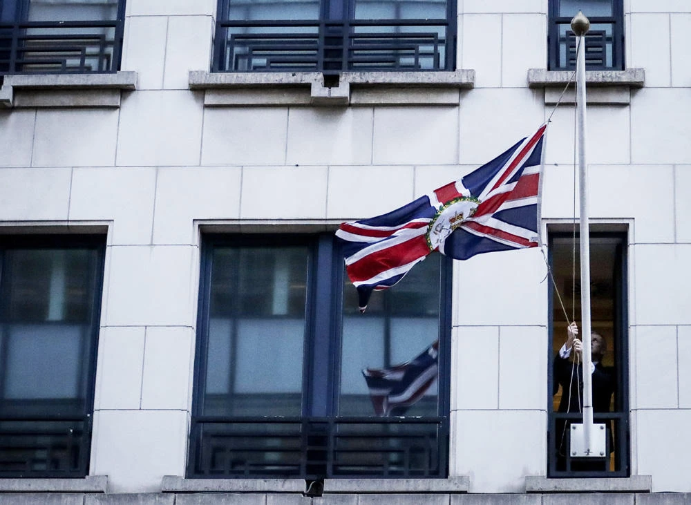 An official handles a United Kingdom flag after removing the European Union flag at the United Kingdom Representation to the EU building in Brussels, on Brexit Day, January 31, 2020. (AFP / POOL / OLIVIER HOSLET)