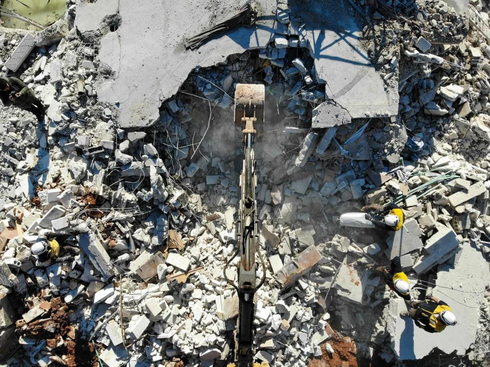 Members of the Syrian Civil Defence, also known as the White Helmets, watch as a bulldozer digs through the rubble of a house hit in a reported airstrike in the town of Sarmin in the northern Syrian Idlib province on February 2, 2020. (AFP)