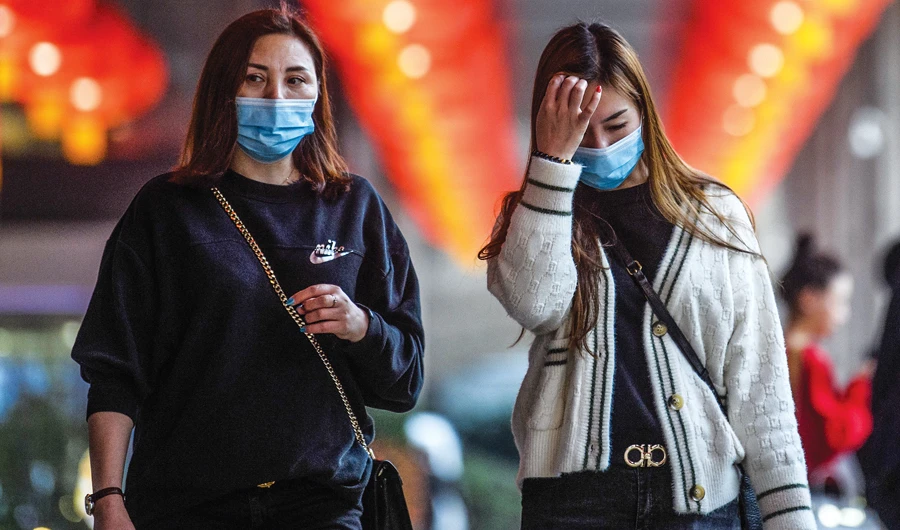Pedestrians wear face masks as they walk outside a hotel in Macau. Several countries have imposed travel restrictions to prevent the spread of the virus. (AFP)