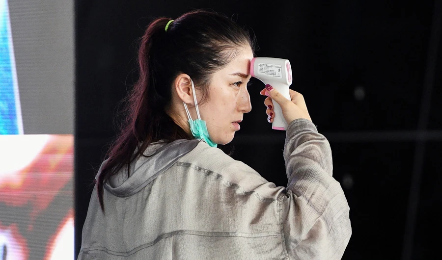 A passenger checks herself with a digital infrared forehead thermometer measurement device at Kuala Lumpur International Airport in Sepang on February 4, 2020. (AFP)