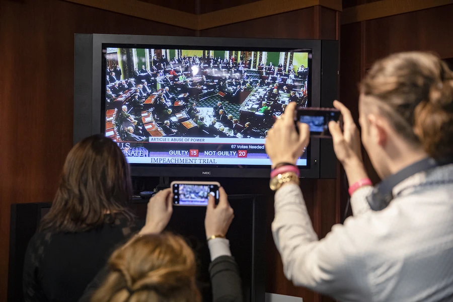 Reporters take photos of the television as they watch the Senate vote on whether or not to acquit President Donald Trump on the two articles of impeachment brought by the House of Representatives to the Senate for trial on Capitol Hill on February 5, 2020 in Washington, DC. (AFP)