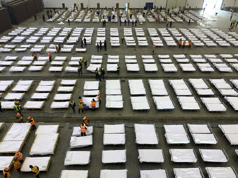 Workers arrange beds in a convention center that has been converted into a temporary hospital in Wuhan in central China's Hubei Province, on Feb. 4, 2020. (Chinatopix via AP)