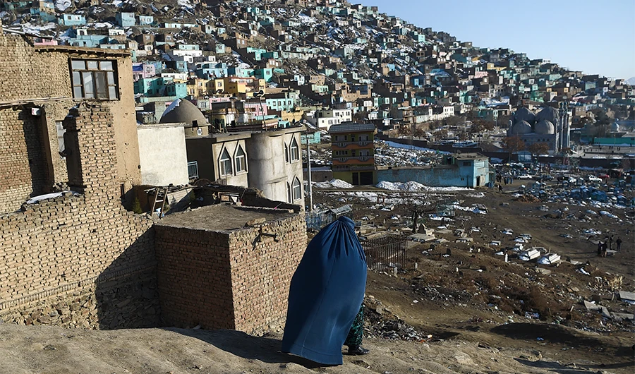 A burqa-clad woman walks down a path near the Kart-e-Sakhi cemetery in Kabul on February 6, 2020. (AFP)