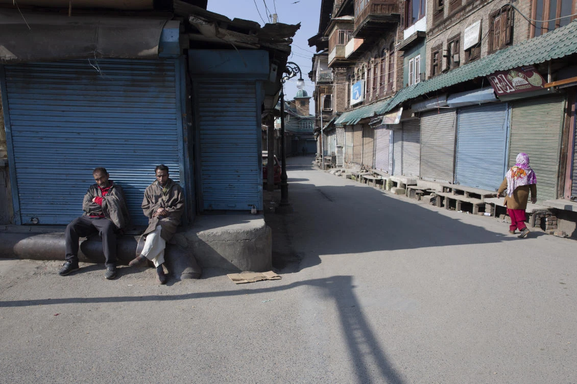 Men sit outside a closed market during a strike in Srinagar, Indian-controlled Kashmir on Sunday, Feb. 9, 2020. (AP)